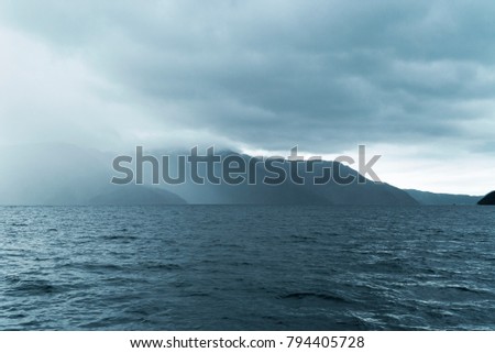 Rough stormy waters and seas with mountains and clouds and fog on the Marlborough Sounds in Picton, New Zealand.