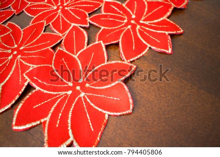 A red and gold poinsettia motif table runner set on dark brown table.