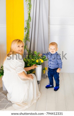 mother with a young son look at the flower pot in the bright room
