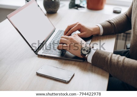 Male hands on laptop keyboard. A laptop with a clean white screen and blank space for text. Side view