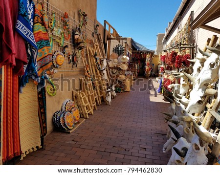 Colorful Spanish/Mexican, Southwestern Art and Textiles for Sale, Outdoors on a Side Alleyway, with Blue Skies and Bright Artwork on Both Sides of Alley; Travel, Tourism, Shopping Royalty-Free Stock Photo #794462830