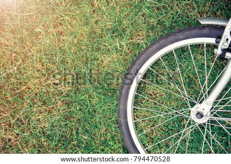 Bike concept background. Close up of bike wheel on green grass with sunlight. Sport and healthy. Picture for add text message. Backdrop for design art work.