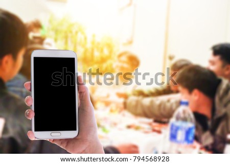 Man use mobile phone, blur images of party between friends as background.