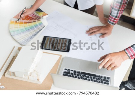 Creative or Interior designers teamwork with pantone swatch and building plans on office desk, architects choosing color samples for design project 