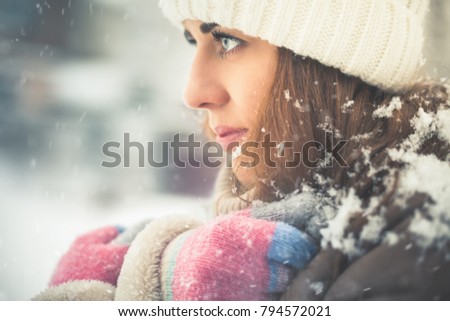 Beautiful woman at cold and snowy winter walking at New York city. Warmly dressed in a coat with a hat.