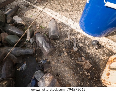 A close up of bottles and crack pipes left on the ground.