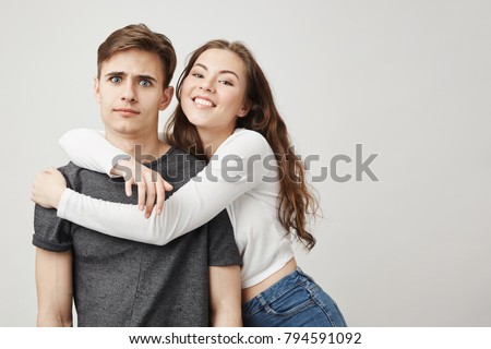 Confused boyfriend and his clingy girlfriend. Girl is very jealous and she do not want her boyfriend go anywhere without her. She always acts weird when there are women near. What an attitude. Royalty-Free Stock Photo #794591092