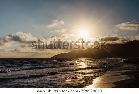 Sunlight sunset on horizon ocean on background seascape atmosphere rays sunrise. Relax view waves sea with kitesurfing on sand beach,  sun light flare nature evening concept, copy space for text
