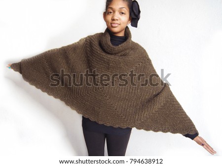 happy african american girl wrapped in warm brown poncho made by craftsman with knitting