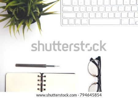 White office desk table with computer keyboard,spectacle,note book,pen,small green plant and pinecones.Top view with copy space.Flat lay.
