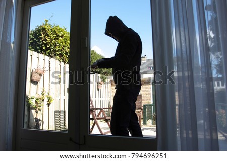 A burglar tries to break in a house Royalty-Free Stock Photo #794696251