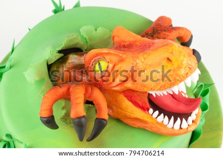 Art cake with orange dinosaur, decorated with green leaves. Gift for the boy. Picture for a menu or a confectionery catalog.