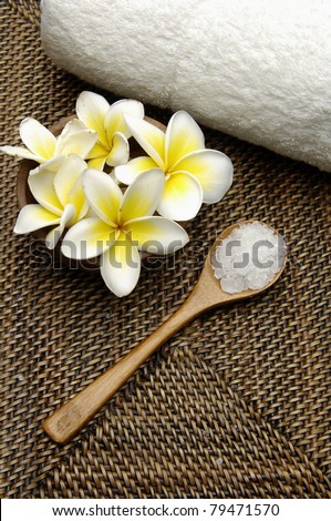 frangipani in bowl with towels and herbal salt in spoon on mat
