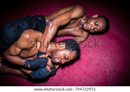 Two African American opponents struggling for dominance in ground fighting during MMA match