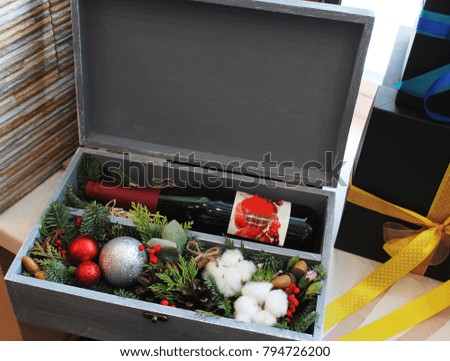 Gray box with gift. A bottle of red wine, spruce branches, Christmas balls