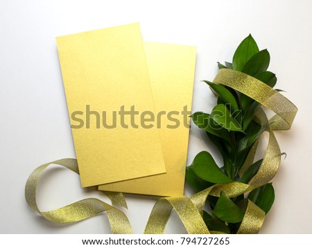 Cards from gold paper, branch with green leaves and gold ribbon  on the white background, top view.