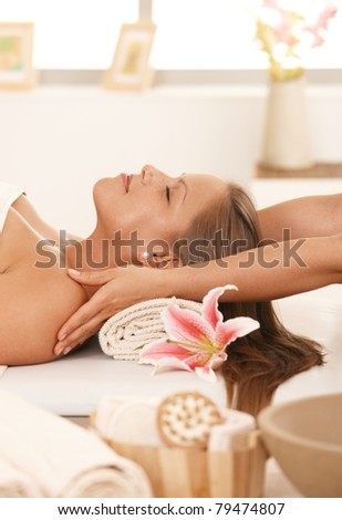 Young woman lying on bed in day spa, enjoying massage with closed eyes.?
