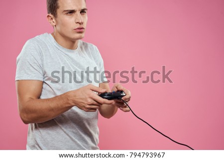   the man plays the console with a joystick on a pink background                             