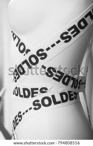 closeup of discount sign "SOLDES" on mannequin in french,  the traduction of the verb "to sold" in english , (a common name is not a brand ) on ribbon   in french fashion store showroom 