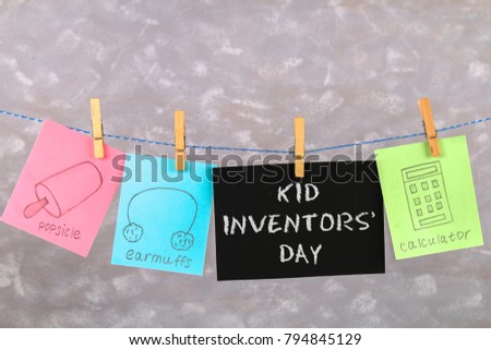 Notes hang on clothes pegs with drawings of children's inventions - popsikl, Earmuffs, calculator on a gray background. Text - Kid Inventors' Day
