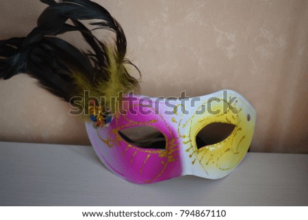 pink and yellow mask with feathers