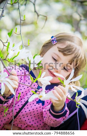 A child in the blooming garden of a magnolia. Selective focus. 