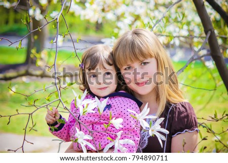 A child and mother in the blossoming magnolia garden. Selective focus. 