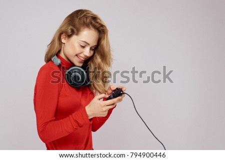 woman young smiling at the neck with headphones in the hand joystick on a light background                               