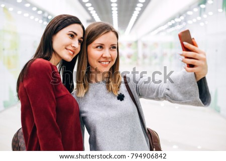 Two young girlfriends stopped to take a selfie on the phone
