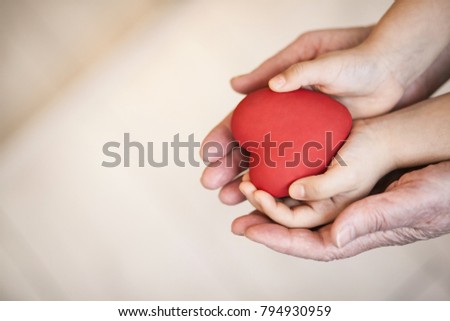 Red heart in child and grandmother's hands