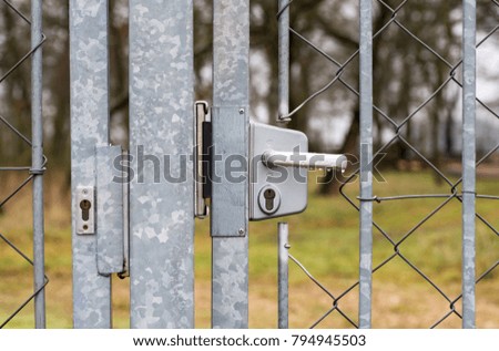 Tin closed door with lock and handle on fence mesh