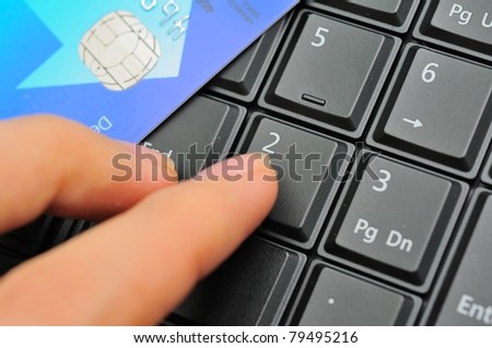 Finger and credit card on black keypad, entering password.