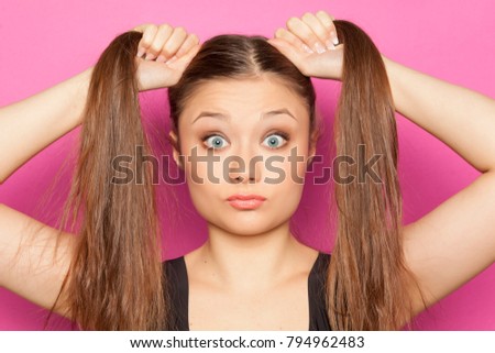young startled girl with ponnytails on a pink background