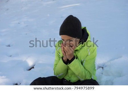 Cute boy is feeling cold, freezing. Try to warm himself blowing  Royalty-Free Stock Photo #794975899