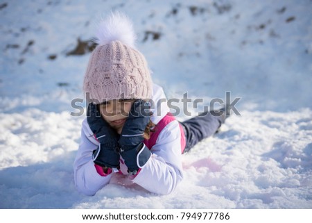 A cute little girl plays on snow. Copy negative spase. Selective focus