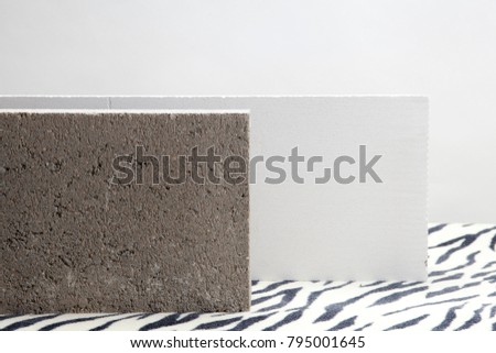 2 concrete blocks on a zebra patterned carpet. Minimal color still life photography