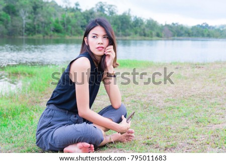 Summer portrait of young hipster woman sitting on a grass in Lake and mountain. image for nature, person, portrait, leisure, lifestyle and vacation concept