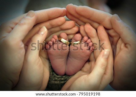 Closeup of parents hands holding newborn baby feet with wedding rings. The concept of the family. Royalty-Free Stock Photo #795019198