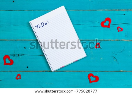 To Do: on blank spiral notebook by red hearts design on antique rustic teal blue wood background; white sign with Valentines Day holiday and  love concept with copy space