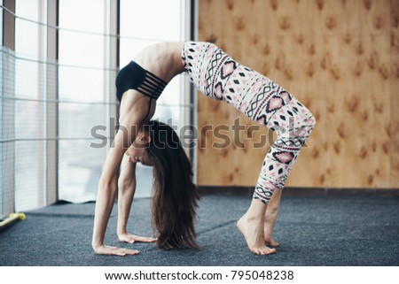 Young attractive woman practicing yoga on the floor near window at the gum