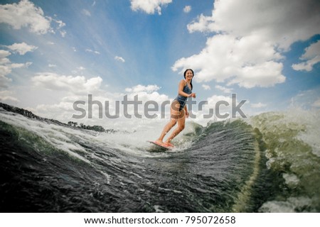 Beautiful brunette woman with wet long hair riding wakeboard in a summer river,having healthy summertime