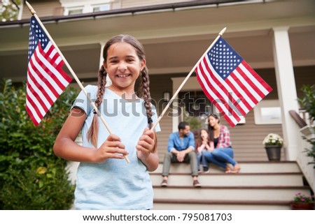 Portrait Of Girl Outside Family Home Holding American Flags
