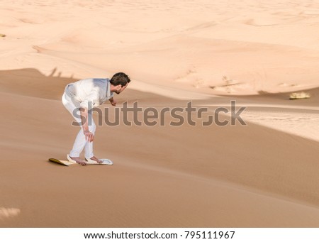 Young man sand boarding in the Dubai desert sand dunes