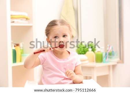 Cute little girl brushing teeth in bathroom