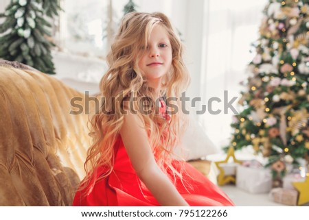 Cute little girl in red dress celebrating cristmass at home