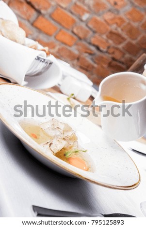 Broth with dumplings and an egg yolk being poured from a jug
