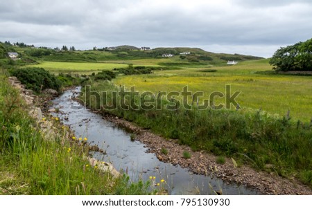 Scottish Burn. A scenic view across a large stream to the rolling landscape and countryside of the Highlands of Scotland.