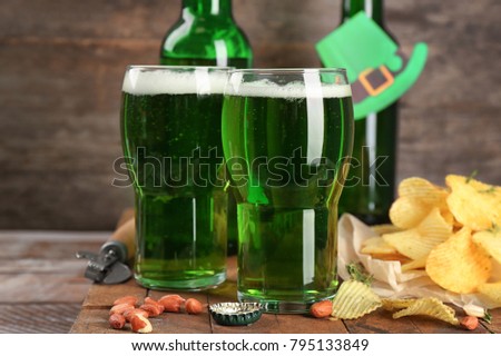 Glasses of green beer and snacks on wooden table. Saint Patrick's day celebration