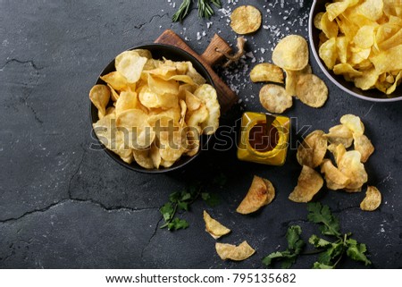 Bowl of home made potato chips served with mustard, rosemary, fleur de sel salt on stone background. Top view. Copy space Royalty-Free Stock Photo #795135682