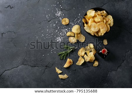 Bowl of home made potato chips served with mustard, rosemary, fleur de sel salt on stone background. Top view. Copy space Royalty-Free Stock Photo #795135688
